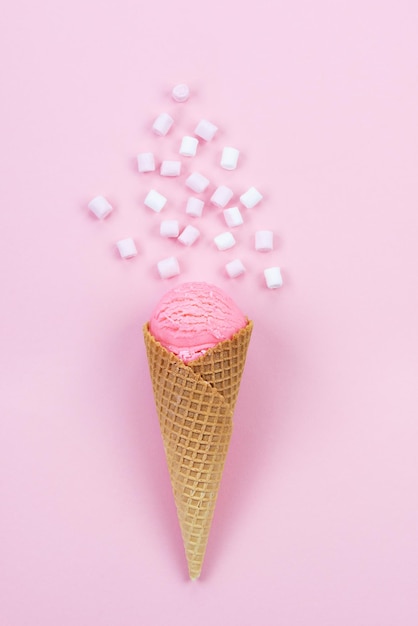 Aardbeienroomijs in een hoorntje met marshmallows op een roze achtergrond