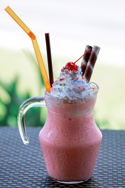 Aardbeiensmoothies milkshake met slagroom en kersen als topping.