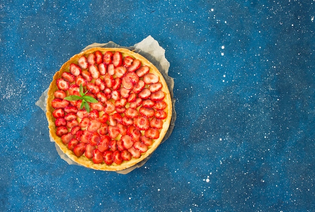 Aardbeientaart gevuld met banketbakkersroom vanille op een blauwe achtergrond