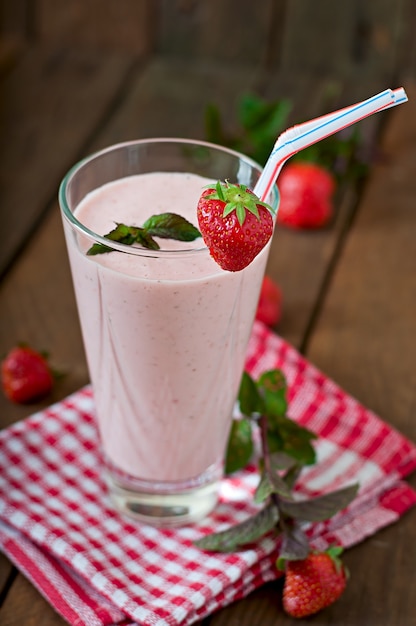 Aardbeimilkshake smoothie met verse aardbei op een houten lijst