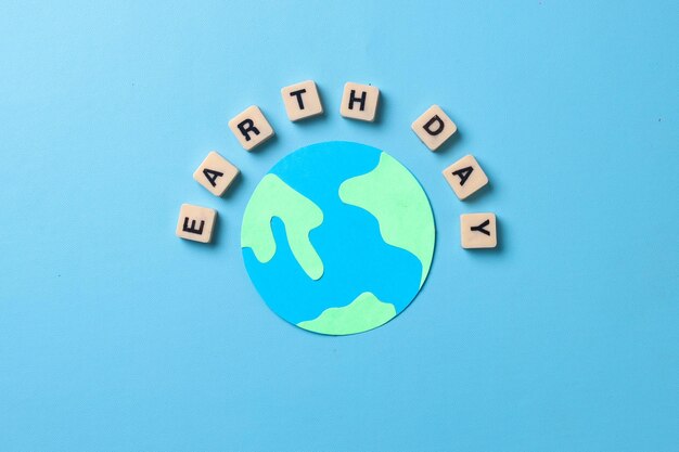 aarde dag woorden met wereldbol gemaakt van papier geïsoleerd op blauwe achtergrond. Wereld aarde dag concept.