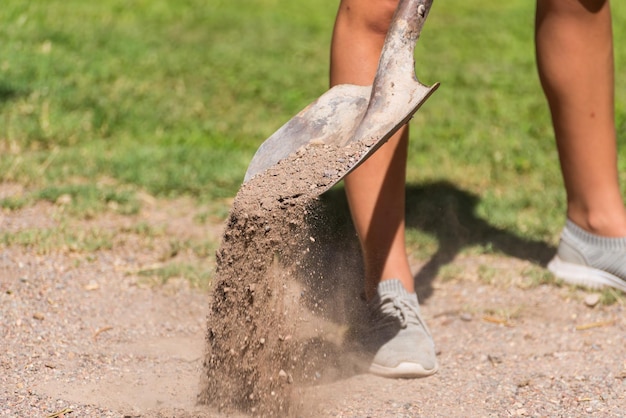 Aarde die van een schop valt die in de benen van de grondvrouw werkt