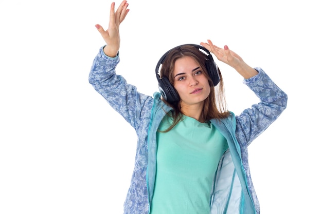 Aardige jonge vrouw met lang bruin haar in blauw shirt in zwarte koptelefoon op witte achtergrond in studio