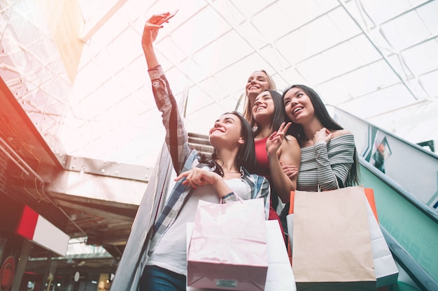 Aardige meisjes nemen selfie op de roltrap in het winkelcentrum