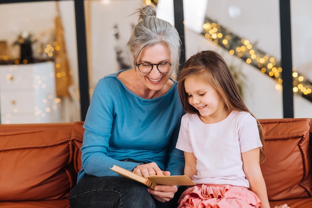 Aardige oma van een oudere vrouw die verhaal voorleest aan kleindochter Gelukkig gezin thuis concept