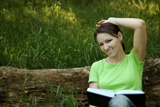 Foto aardige vrouw die een boek leest in de natuur