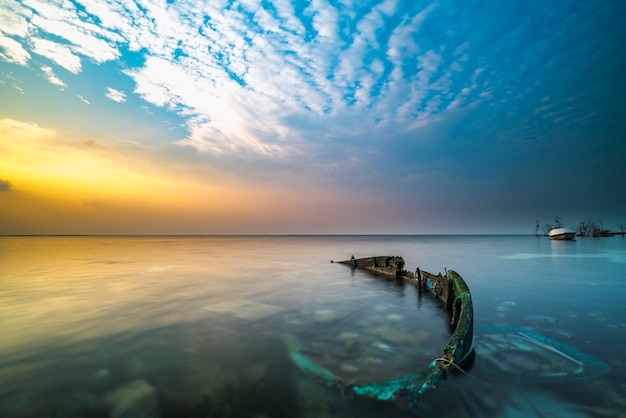 Photo abandon boat sinking with sunrise background