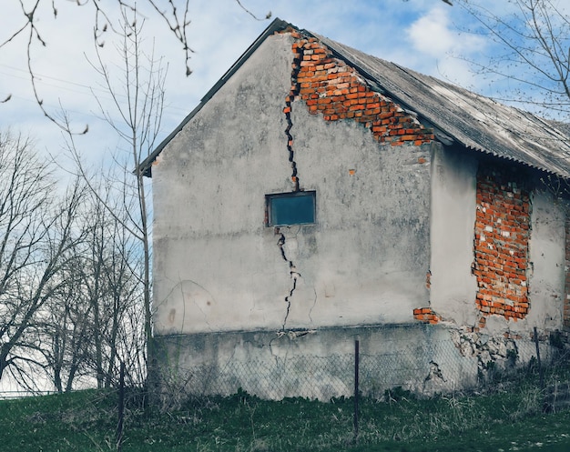 Photo abandoned barn in a weed yard cracks in the brick walls apocalyptic background