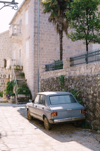 Abandoned blue car parked near a stone building