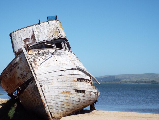 Foto una barca abbandonata sul mare contro un cielo limpido