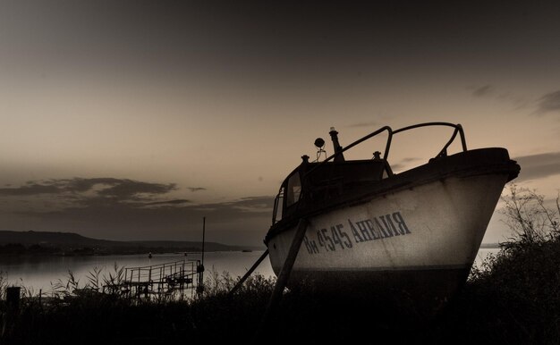 Foto barca abbandonata ormeggiata sulla spiaggia contro il cielo durante il tramonto