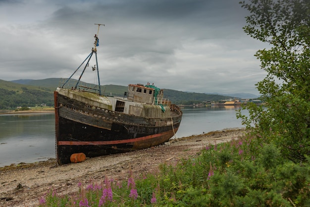 Abandoned boat moored on beach against sky