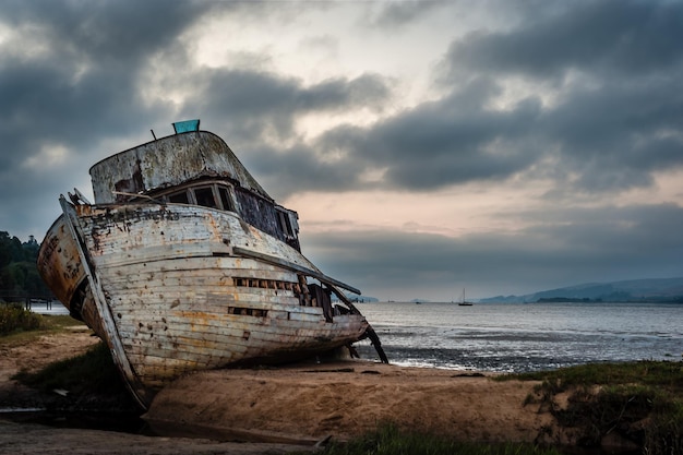 写真 空に向かってビーチに停泊した放棄されたボート