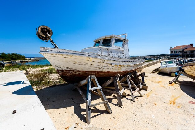 Abandoned boats moored on beach against blue sky