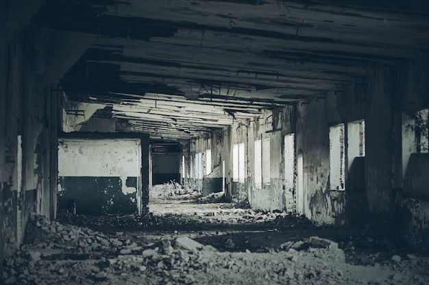 Abandoned building interior, dark spooky scary corridor in vintage dirty broken ruined abandoned premises, ruins of old industrial factory, grungy urban background