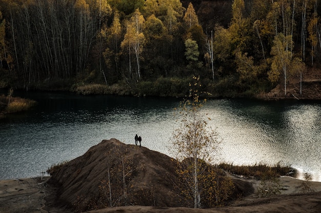 Abandoned coal mine, hills of brown sand. Waste production mines. Industrial landscape in autumn with yellow birches against a gray sky.