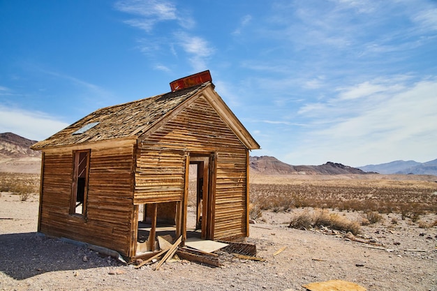 Abandoned ghost town house of wood in desert by mountains