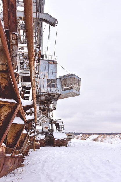 Abandoned giant bucket wheel excavator stands in a field in winter