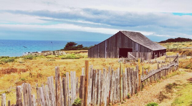 Abandoned house on field against cloudy sky