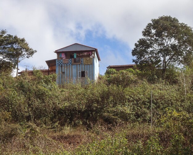 Foto casa abbandonata sul campo dagli alberi contro il cielo