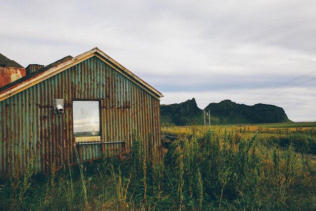 Photo abandoned house on grassy field against cloudy sky