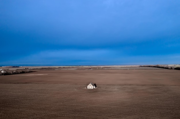 An abandoned house in the middle of a field against a stormy sky