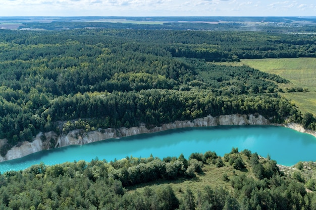 Abandoned mountain quarry. The mine workings are filled with water of a deep blue color. Aerial view