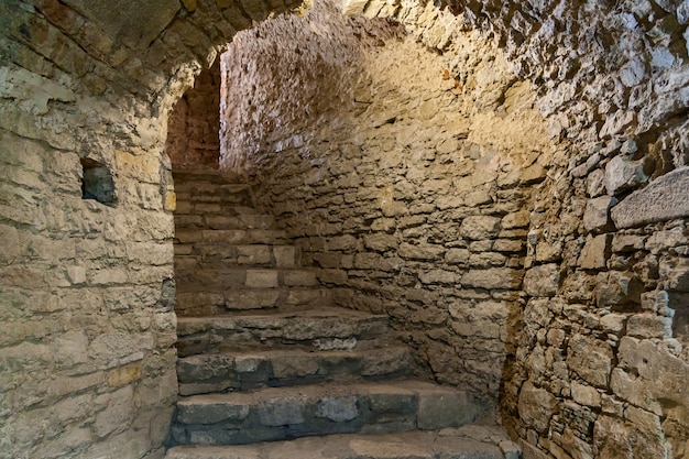 Abandoned old stairs with cracked walls to a basement of an old\
fortress.