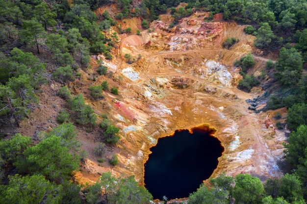 Abandoned open pit mine near Mathiatis, Cyprus. Aerial view on acidic red lake and colourful mine tailings left after pyrite ore extraction