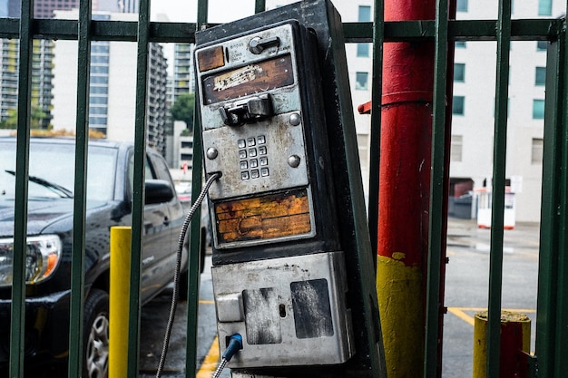 Photo abandoned pay phone by railing in city