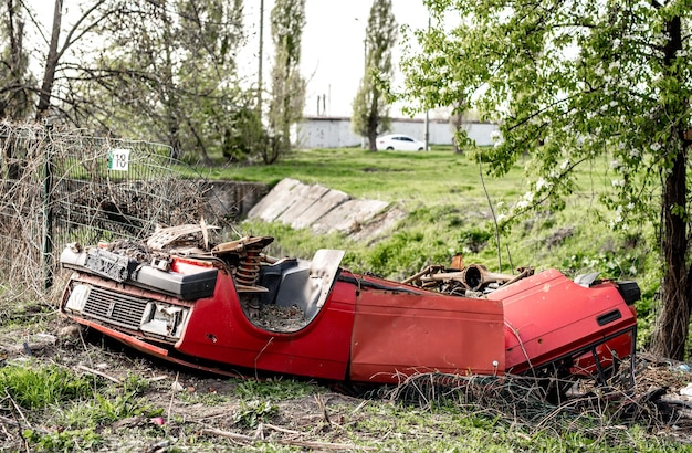 Заброшенный красный автомобиль с повреждениями во время войны