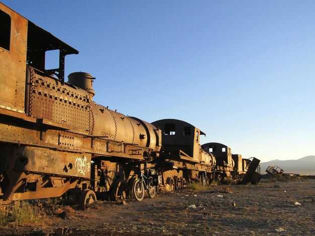 Abandoned train on field against clear sky