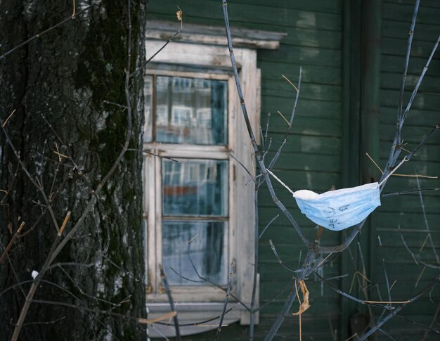 Фото Заброшенная использованная медицинская маска, привязанная к ветвям деревьев