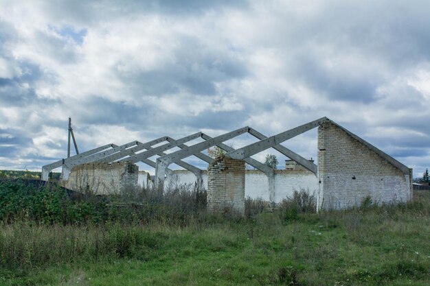 An abandoned white brick building with a triangular roof.