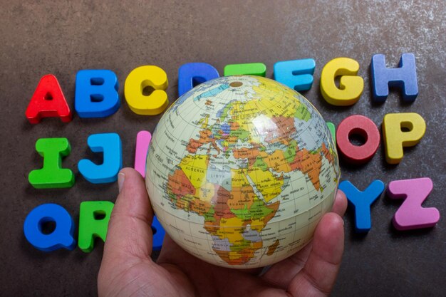 Foto lettere dell'alfabeto abc e globo in mano come concetto di educazione