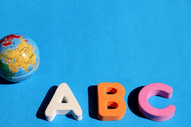 ABC first letter of the English alphabet and small globe on blue 