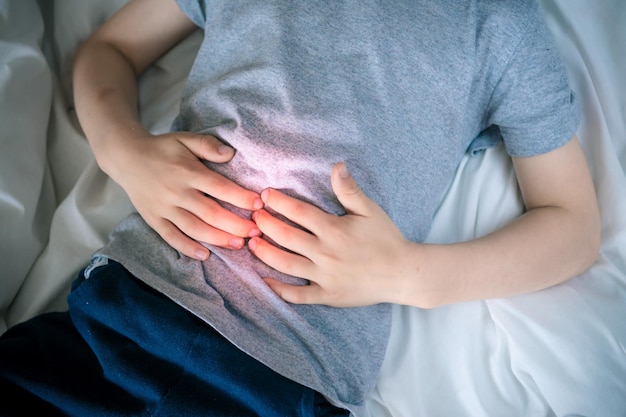 Photo abdominal pain in a preschool child poisoning in children the boy holds his hands to the abdominal cavity