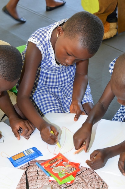 Абиджан / берег слоновой кости - 1 декабря 2015 г .: 8-летняя ивуарская школьница рисует на белой бумаге.