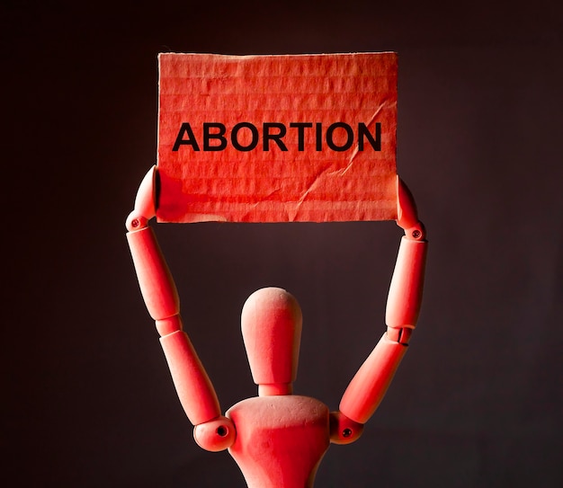 Photo abortion word on placard in hands in red light