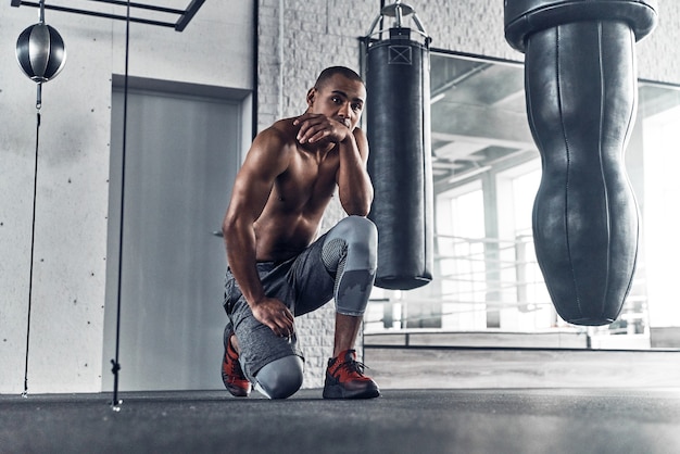 About to do another exercise. Shirtless young African man looking away 