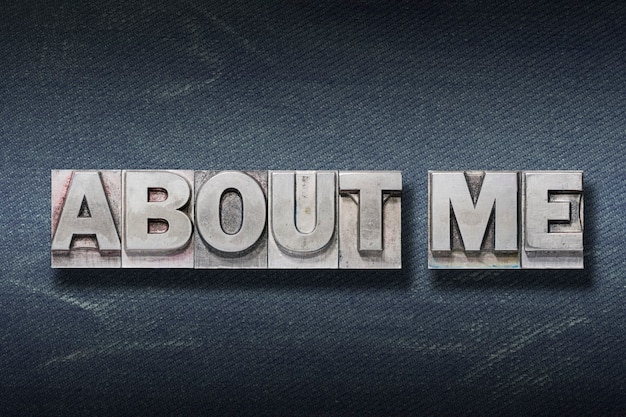 About me phrase made from metallic letterpress on dark jeans background