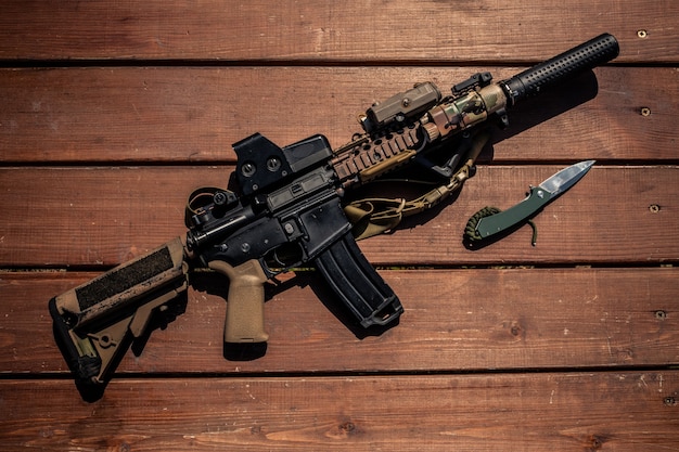 사진 나무 탁자에 있는 현대적인 소총과 칼의 위, 군인 무기 개념