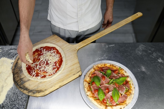 写真 プロのキッチンでピザのベースを準備するシェフの手の上のビュー