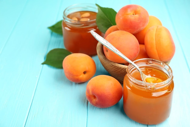 Abrikozenjam in potten met lepel en rijp sappig fruit op tafel