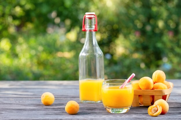 Abrikozensap en abrikozen in mand op houten tafel