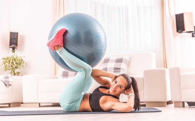 Abs exercise using a fit ball performed by an attractive athletic sportswoman at home.