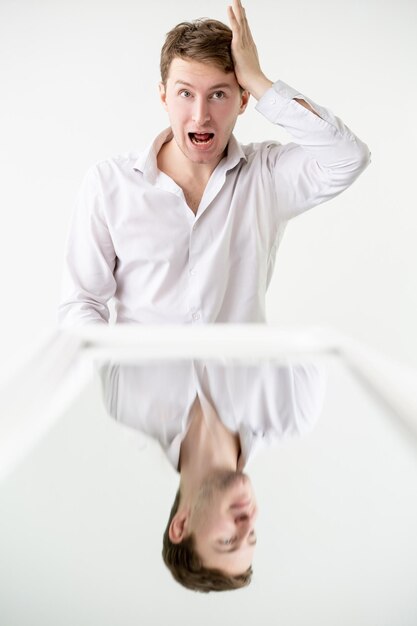 Absent man Mental stress Anxiety panic Psychology disorder Conceptual art Inversion illusion Shocked guy grasping head while calm smiling reflection in mirror isolated on white