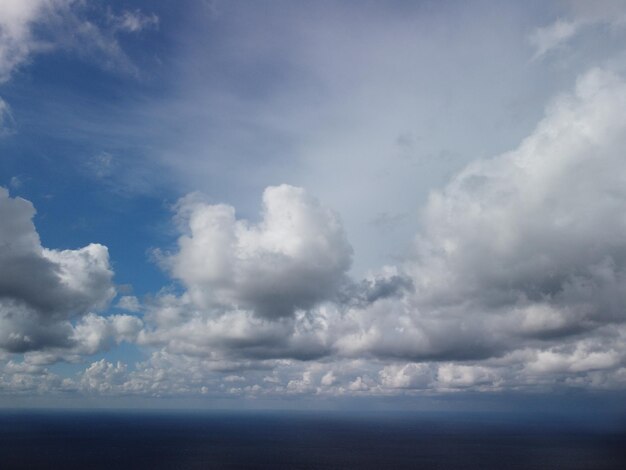 写真 澄んだ水面の海の海の小さな波の上に移動するふっくらとした雲と抽象的な風通しの良い空