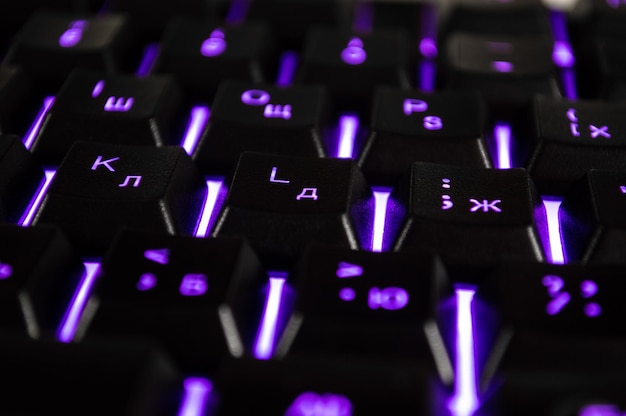 Sfondo astratto della tastiera del computer nero con retroilluminazione viola la foto del primo piano con bokeh può essere utilizzata come sfondo