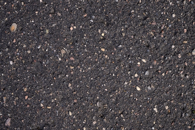 Photo abstract background of black wet asphalt with inclusions of pebbles